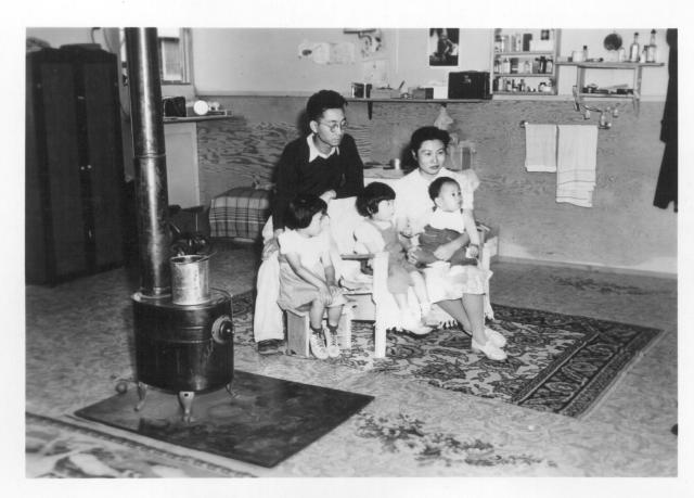 An evacuee family spends a quiet evening in their barracks. The decoration of this apartment is quite typical and shows the home made furniture, shelves, bookcases and other furniture. -- Photographer: Stewart, Francis -- Newell, California. 9/10/42. Source.